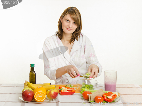 Image of Housewife holds over a cup of salad with chopped vegetables