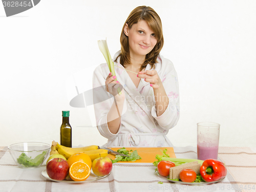 Image of Happy housewife cleans the rind salad with celery cooking