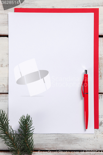 Image of The blank sheet of paper on the wooden table with a pen 