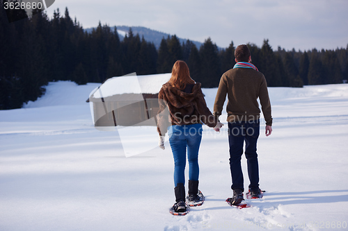 Image of couple having fun and walking in snow shoes