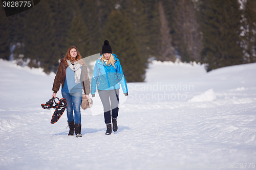 Image of female friends in beautiful winter day have relaxed walk on snow