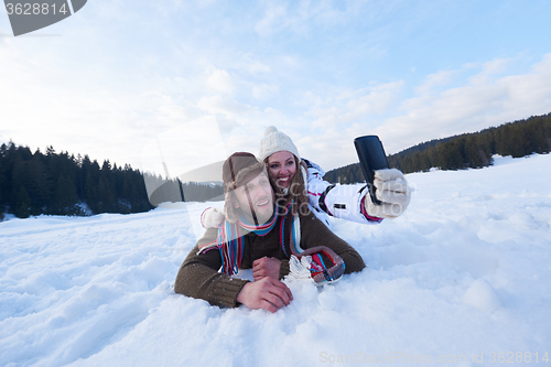 Image of romantic couple have fun in fresh snow and taking selfie