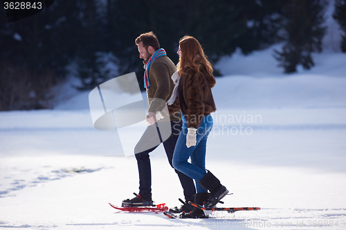 Image of couple having fun and walking in snow shoes