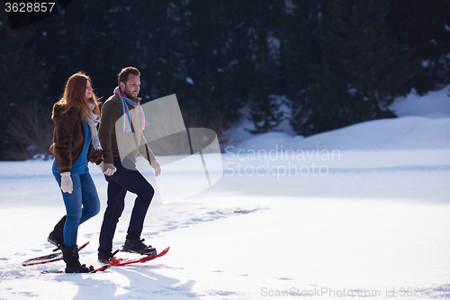 Image of couple having fun and walking in snow shoes