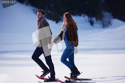 Image of couple having fun and walking in snow shoes