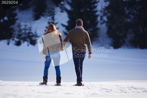 Image of couple having fun and walking in snow shoes