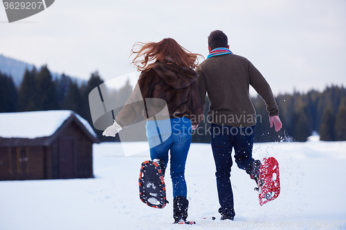 Image of couple having fun and walking in snow shoes