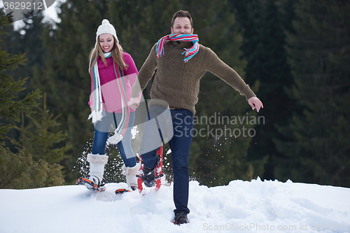 Image of couple having fun and walking in snow shoes