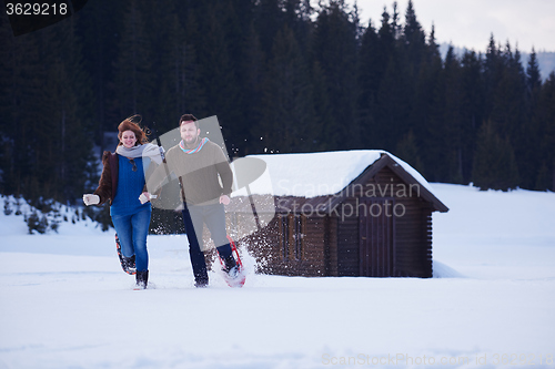 Image of couple having fun and walking in snow shoes