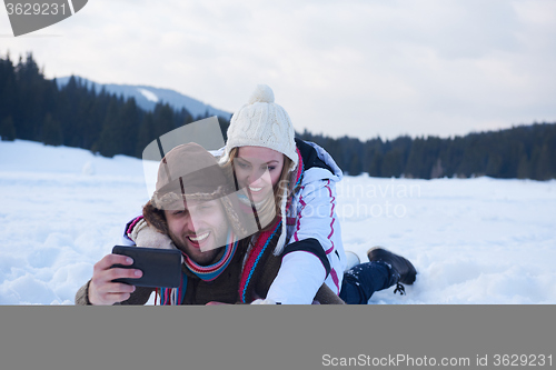Image of romantic couple have fun in fresh snow and taking selfie