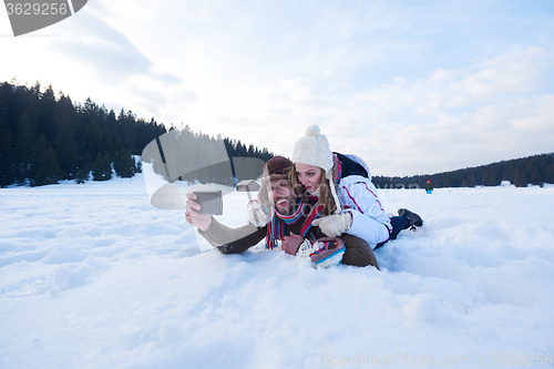 Image of romantic couple have fun in fresh snow and taking selfie