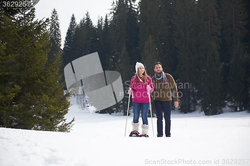 Image of couple having fun and walking in snow shoes