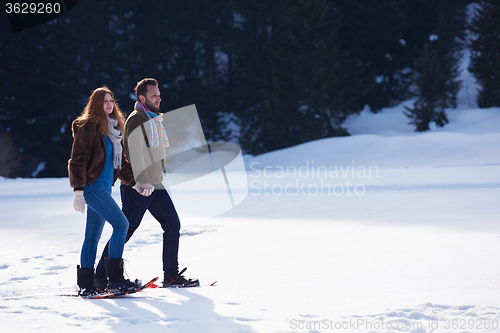 Image of couple having fun and walking in snow shoes