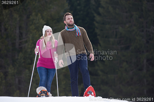 Image of couple having fun and walking in snow shoes