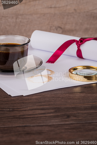 Image of Coffee cup, paper sheets and detective hat