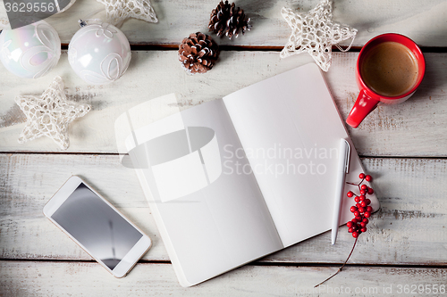 Image of The open notebook on the wooden table with a phone