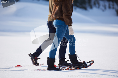 Image of couple having fun and walking in snow shoes