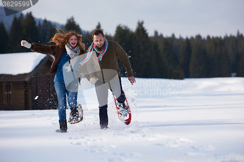 Image of couple having fun and walking in snow shoes