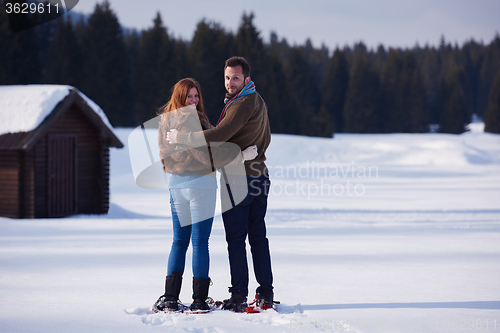 Image of couple having fun and walking in snow shoes