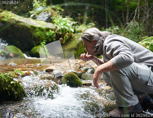 Image of man drinking fresh water from spring