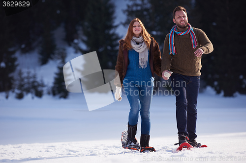 Image of couple having fun and walking in snow shoes