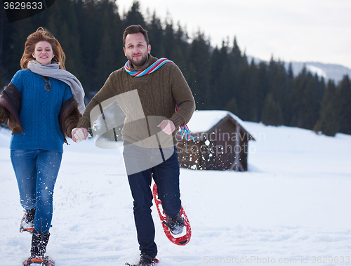 Image of couple having fun and walking in snow shoes