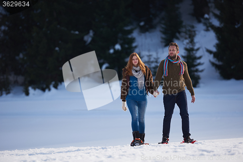 Image of couple having fun and walking in snow shoes