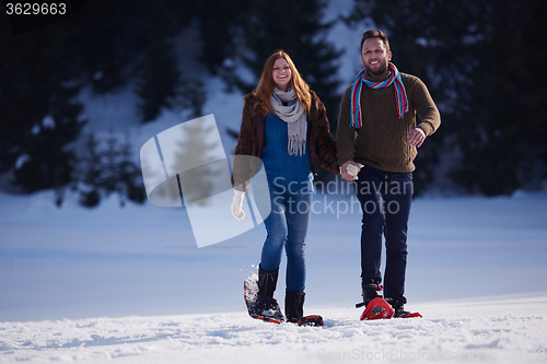 Image of couple having fun and walking in snow shoes