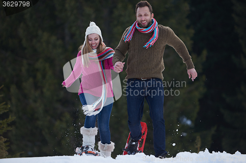 Image of couple having fun and walking in snow shoes