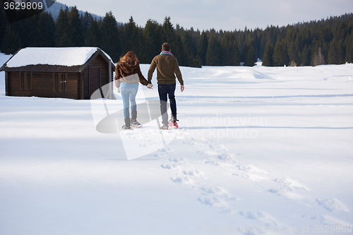 Image of couple having fun and walking in snow shoes