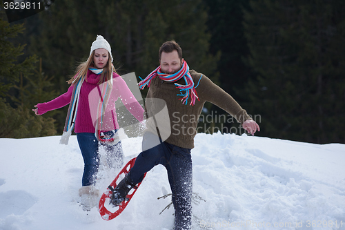 Image of couple having fun and walking in snow shoes