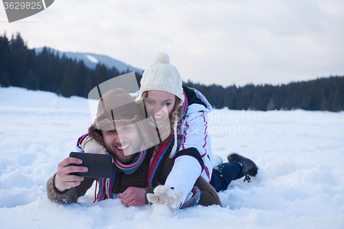 Image of romantic couple have fun in fresh snow and taking selfie