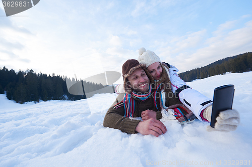 Image of romantic couple have fun in fresh snow and taking selfie