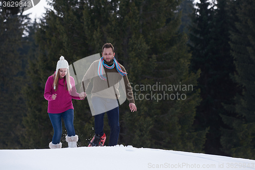 Image of couple having fun and walking in snow shoes