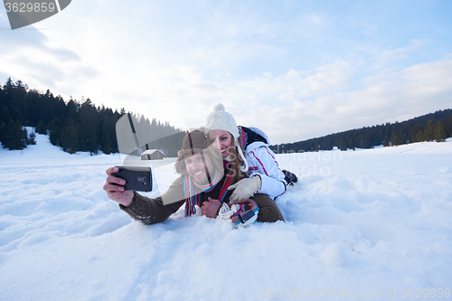 Image of romantic couple have fun in fresh snow and taking selfie