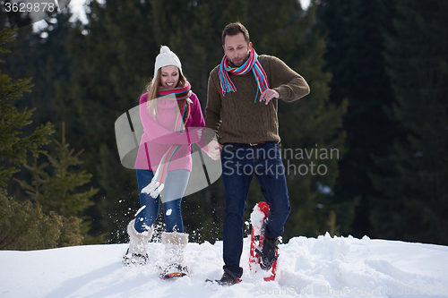 Image of couple having fun and walking in snow shoes