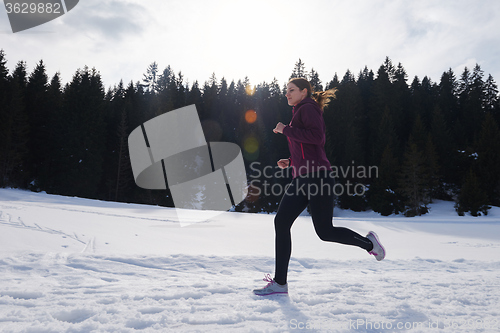 Image of yougn woman jogging outdoor on snow in forest