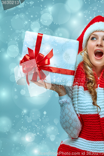 Image of Girl dressed in santa hat with a Christmas gift 