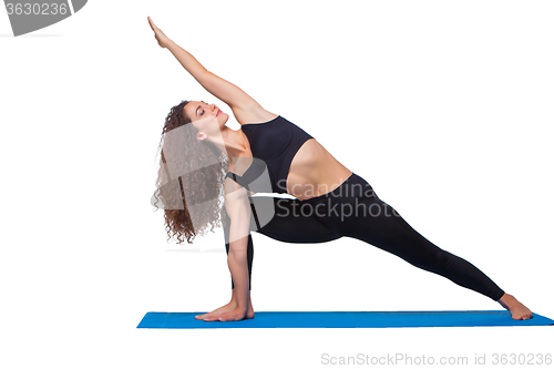 Image of Studio shot of a young fit woman doing yoga exercises.