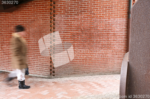 Image of People passing by a brick wall
