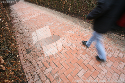 Image of People passing by a brick wall