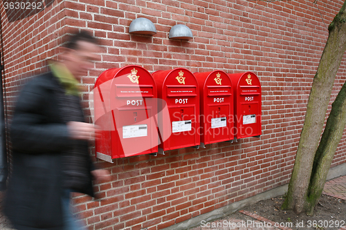 Image of Man and postboxes on a brick wall