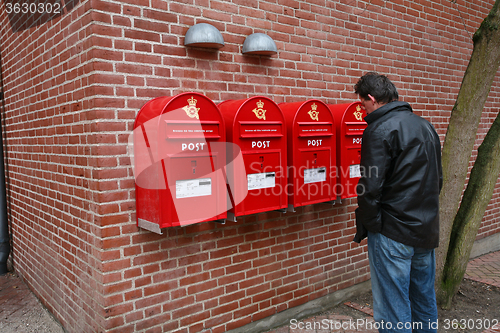 Image of Man and postboxes on a brick wall