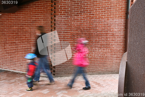 Image of People passing by a brick wall