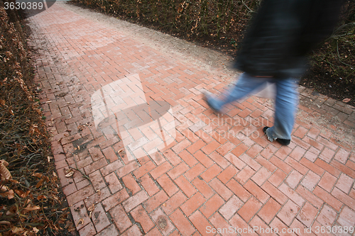 Image of People passing by a brick wall