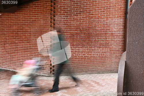 Image of People passing by a brick wall