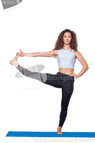 Image of Studio shot of a young fit woman doing yoga exercises.