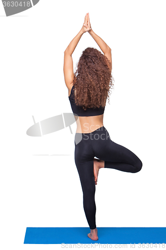 Image of Studio shot of a young fit woman doing yoga exercises.