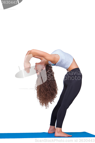 Image of Studio shot of a young fit woman doing yoga exercises.