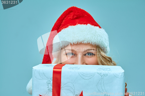 Image of Girl dressed in santa hat with a Christmas gift 